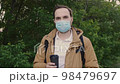 Portrait of a bearded man in a medical protective mask with a cup of coffee. Middle shot. 98479697