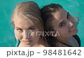 Top view video of two sexy women in swimsuit posing in outdoor swimming pool 98481642