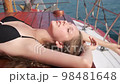 Pretty young girl in swimming suit lying on wooden deck, relaxing and sunbathing 98481648