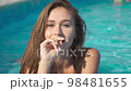 Sexy woman smiling, flirting, lying in swimming pool at summer resort 98481655