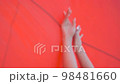 Beautiful slim woman in a black swimming suit is posing on a red background 98481660