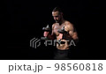Strong handsome shirtless sport man training biceps with dumbbells on black background 98560818