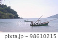 Boat floating on a sea near the beach of Thailand. Island and bright sky at background. slow motion. 98610215