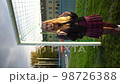 Blonde woman in skirt and lather jacket stands near soccer net at sport field 98726388