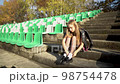 Young blonde girl is sitting on steps on the empty football stadium, 98754478