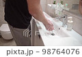 footage of an unrecognizable woman washing her hands in the bathroom 98764076