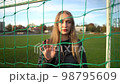 Portrait of young serious girl looking into camera in soccer gate at sport field 98795609