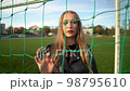 Portrait of young serious girl looking into camera in soccer gate at sport field 98795610