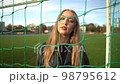 Portrait of young serious girl looking into camera in soccer gate at sport field 98795612