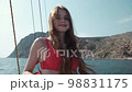 Sweet girl in red swimsuit is fixing her long brown hair and smiling 98831175