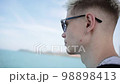 Handsome young man in sunglasses stands on the ship. On a sunny day in summer, against the backdrop of the turquoise sea. slow motion 98898413