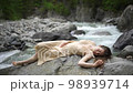 Young attractive woman in a wet water color dress lies on the stones. 98939714