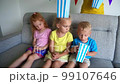 Mother hand give popcorn boxes for children watching tv television. Little kids eating pop corns and watching home cinema. Smooth camera motion shot with gimbal. 99107646