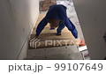 Worker man add stairs board step in staircase. Handheld shot. 99107649