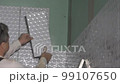 Tiler apply piece of tile on wall. Static closeup shot. 99107650