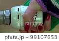close up of woman hand with red nail adjusting the temperature by thermostat radiator in living room. 4K 99107653