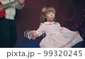 Little girl on stage in pink vintage dress, she dances, her father plays acoustic guitar. Color music is shining. Performance on stage. Early development of children 99320245