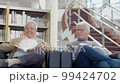 Cheerful senior friends sitting in armchairs in library 99424702