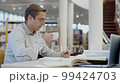 Man drinking tea while studying in library 99424703