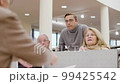 Senior man giving textbook to woman during class in library 99425542