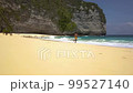 Young happy athletic traveler man running on sandy shore of tropical beach along waves of turquoise water and white foam. Kelingking Beach, Nusa Penida, Indonesia. Travel, Leisure, vacation 99527140