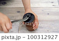 A Japanese woman grinding beans with a coffee mill View from above 100312927