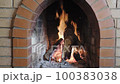 front view of burning firewood in fireplace in brick stove close-up in country house on day 100383038