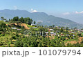 A view of a small village on the top of a hill with the Himalayan Mountains in the background with a panning view. 101079794