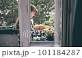 Smiling woman gardening on her balcony with cat 101184287