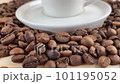 Coffee and a cup with a saucer. In the video, the camera moves smoothly, in the frame there are coffee beans and a white coffee cup with a saucer. 101195052