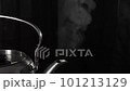 A stainless steel kettle is steaming in front of a black background 101213129