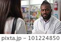 4K high-quality footage showcases the portrait of a male African-American pharmacist as he assists a female customer in buying prescription medicine in drugstore. Pharmacy professionals in healthcare 101224850