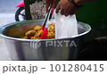 Indonesian local vendor or steet food seller put crispy fried chicken into plastic polypropylene hot bag at market. 101280415