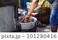 Indonesian local vendor or steet food seller put crispy fried chicken into plastic polypropylene hot bag at market. 101280416