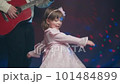 Little girl on stage in pink vintage dress, she dances, her father plays acoustic guitar. Color music is shining and smoke is billowing. Father Day. Performance on stage. Hobbies and creativity 101484899