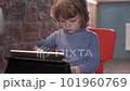 a little boy is interestedly looking at the tablet and eats yogurt 101960769