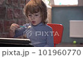 a little boy is interestedly looking at the tablet and eats yogurt 101960770