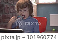 a little boy is interestedly looking at the tablet and eats yogurt 101960774