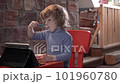 a little boy is interestedly looking at the tablet and eats yogurt 101960780