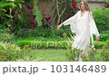 a young girl in a white dress dancing, sewn with her own hands, slow movement and singing outdoors in a religious park, street, having fun alone, emotionally 103146489