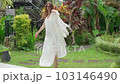 a young woman in a white dress dancing slow motion and singing outdoors in a religious park, a street having fun alone. Young adult happy woman in a white dress dancing,very emotional 103146490