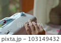 Sewing machine, close-up. Work at home. A beautiful woman sews on a sewing machine in a bright room. A girl sews fabric on a sewing machine 103149432