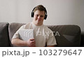 Man with down syndrome at home in headphones, holding laptop 103279647