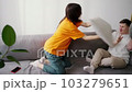 Sister brother fight on sofa with pillows, a woman and a guy with Down syndrome 103279651