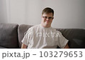 Portrait of happy caucasian man in white T shirt with Down Syndrome sitting on couch at home 103279653