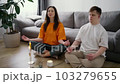 Portrait of a woman assisting guy with down syndrome doing in meditating at home, slow motion 103279655
