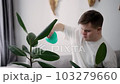 Man with down syndrome spraying houseplants with care 103279660