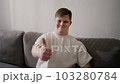Young adult man sitting on sofa, happy with big smile doing ok sign, thumb up with fingers, excellent sign 103280784