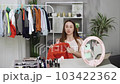 Blogger woman showing casual colorful clothes on camera. Stylist influencer girl showing trendy clothes filming vlog episode for her channel. Opinion leader sets trends 103422362