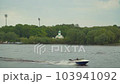 A motor boat is floating on the river. Church in the background of the river. Water tourism by boat. The river overflowed in spring. 103941092